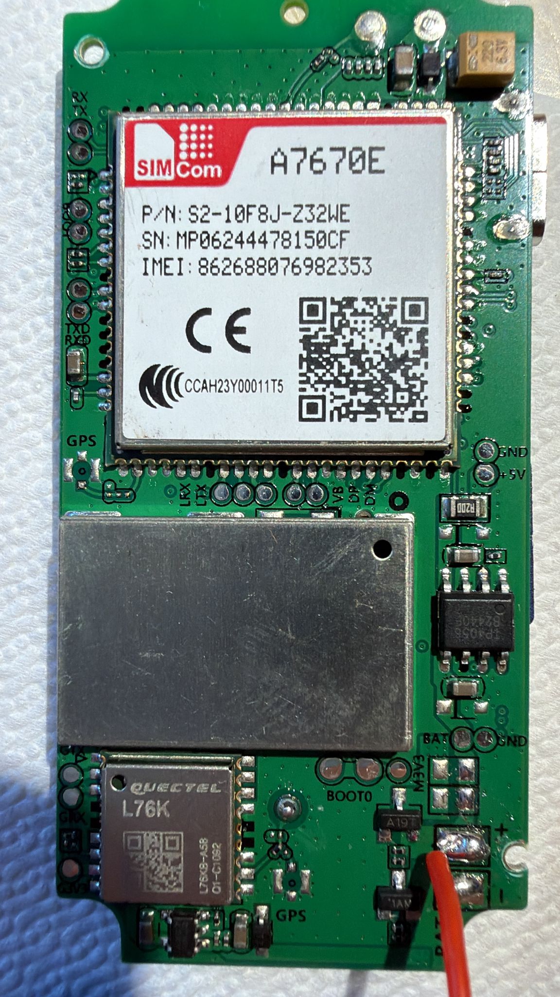 Lato top: SimCom A7670E modem (P/N S2-10F8J-Z32WE) + Quectel L76K GNSS + IC charger SOIC-8 + test pad UART (RX/TX/LRX/LTX/BOOT0)