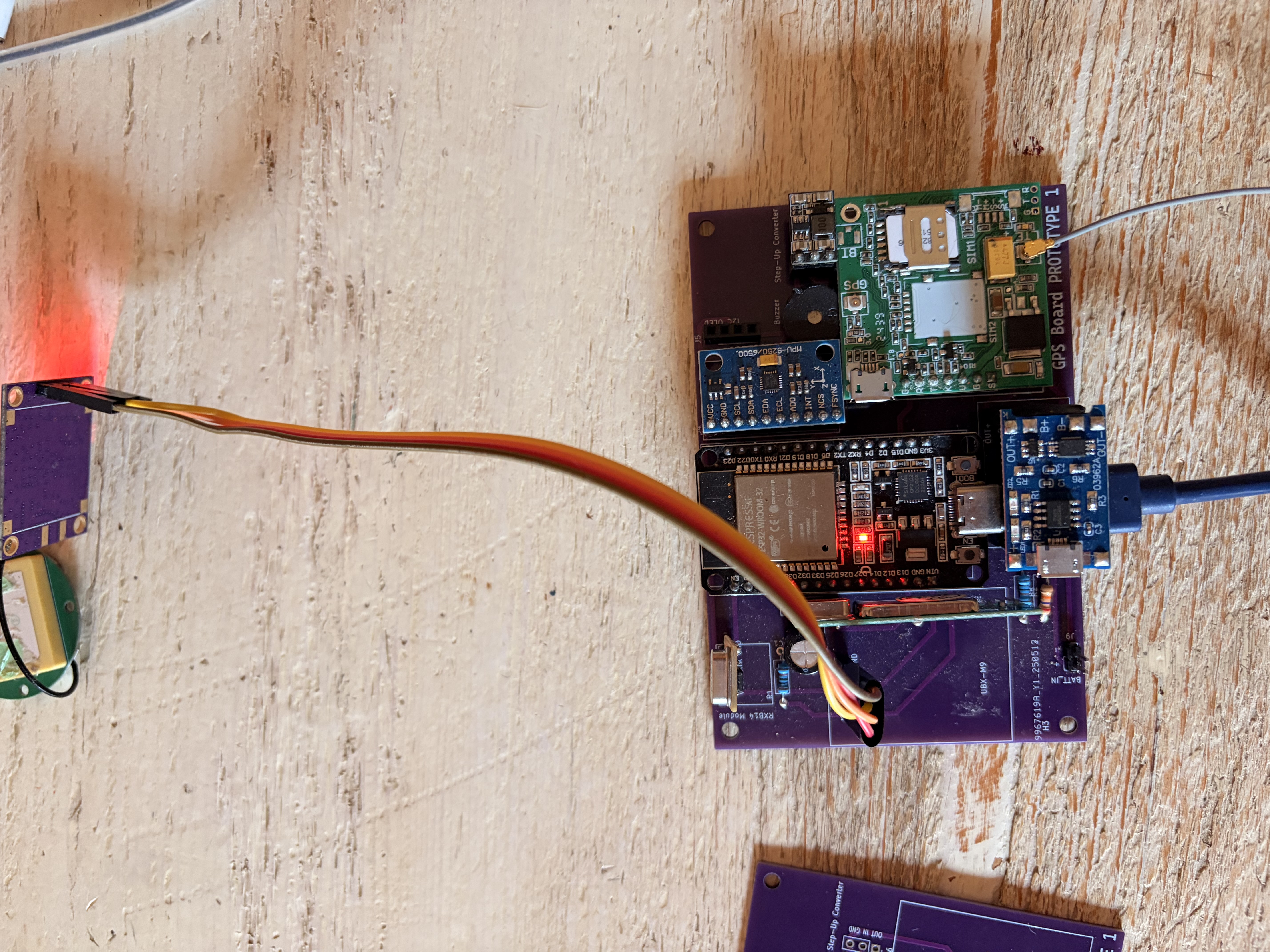 PCB assemblata in modalità "carrier board": moduli plug-in via cavi Dupont colorati. ESP32 DevKit esterno (sostituisce ESP8266 originale), MAX-M10S, A7670E breakout BK-A7670